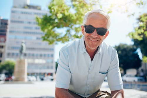 Senior man squinting at phone over coffee, illustrating pre-surgery challenges