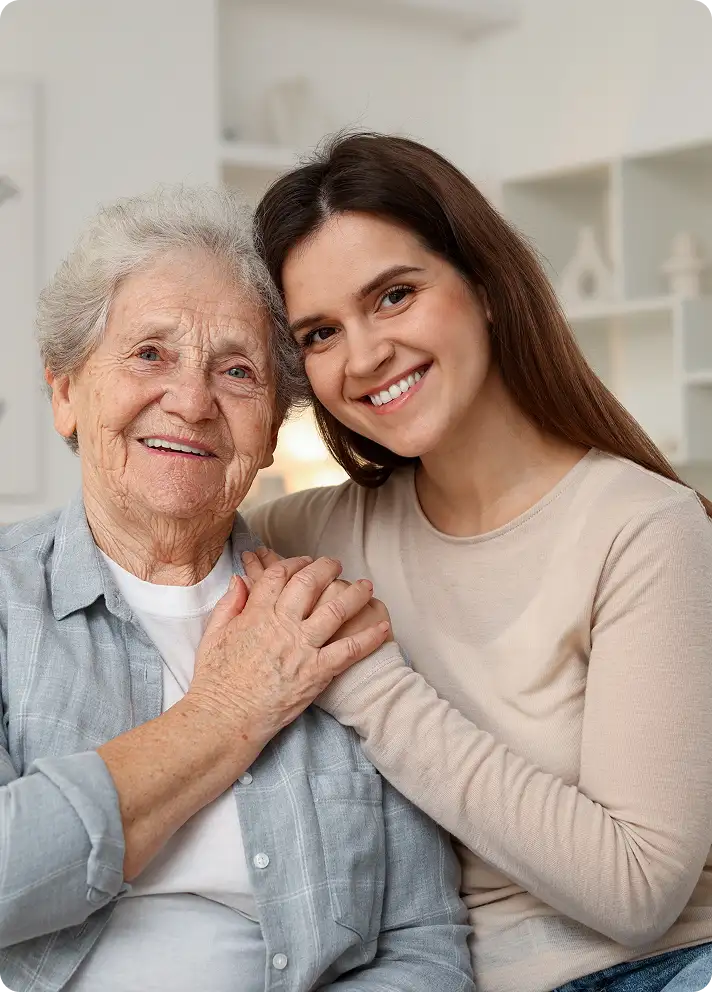 Grandmother and granddaughter embracing on a sofa.