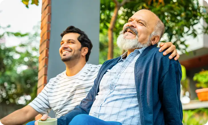 Older man and adult son smiling outdoors.