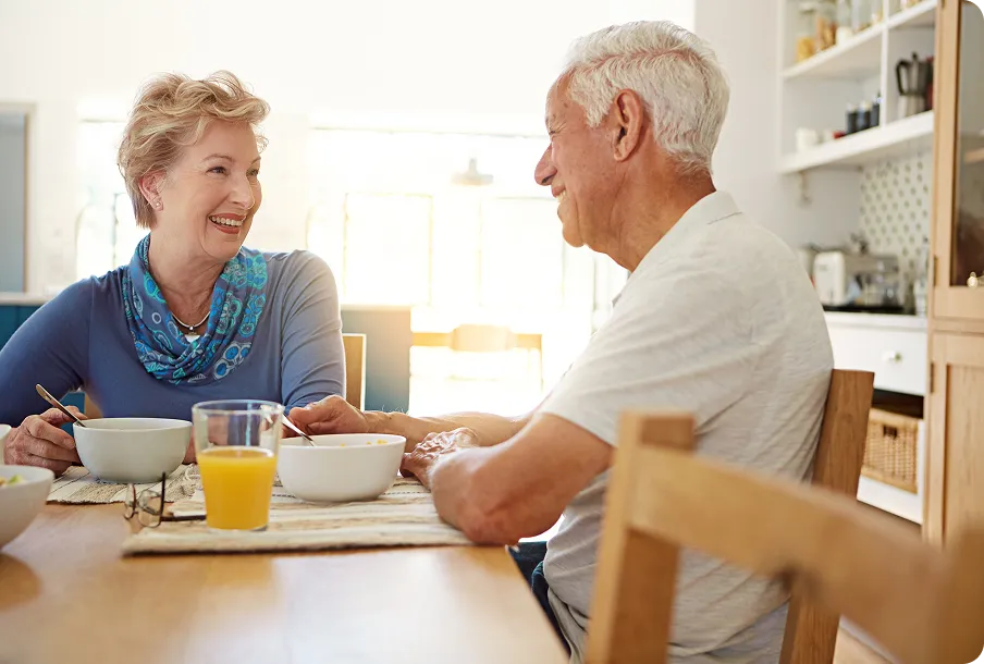Elderly couple at sunny breakfast table – vitality with cataract IOLs clear vision.